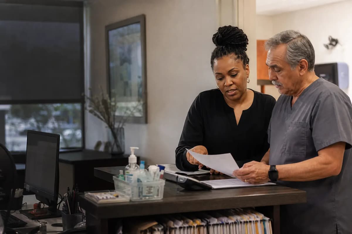 A clinic coordinator and clinician reviewing the day at a private front-office counter